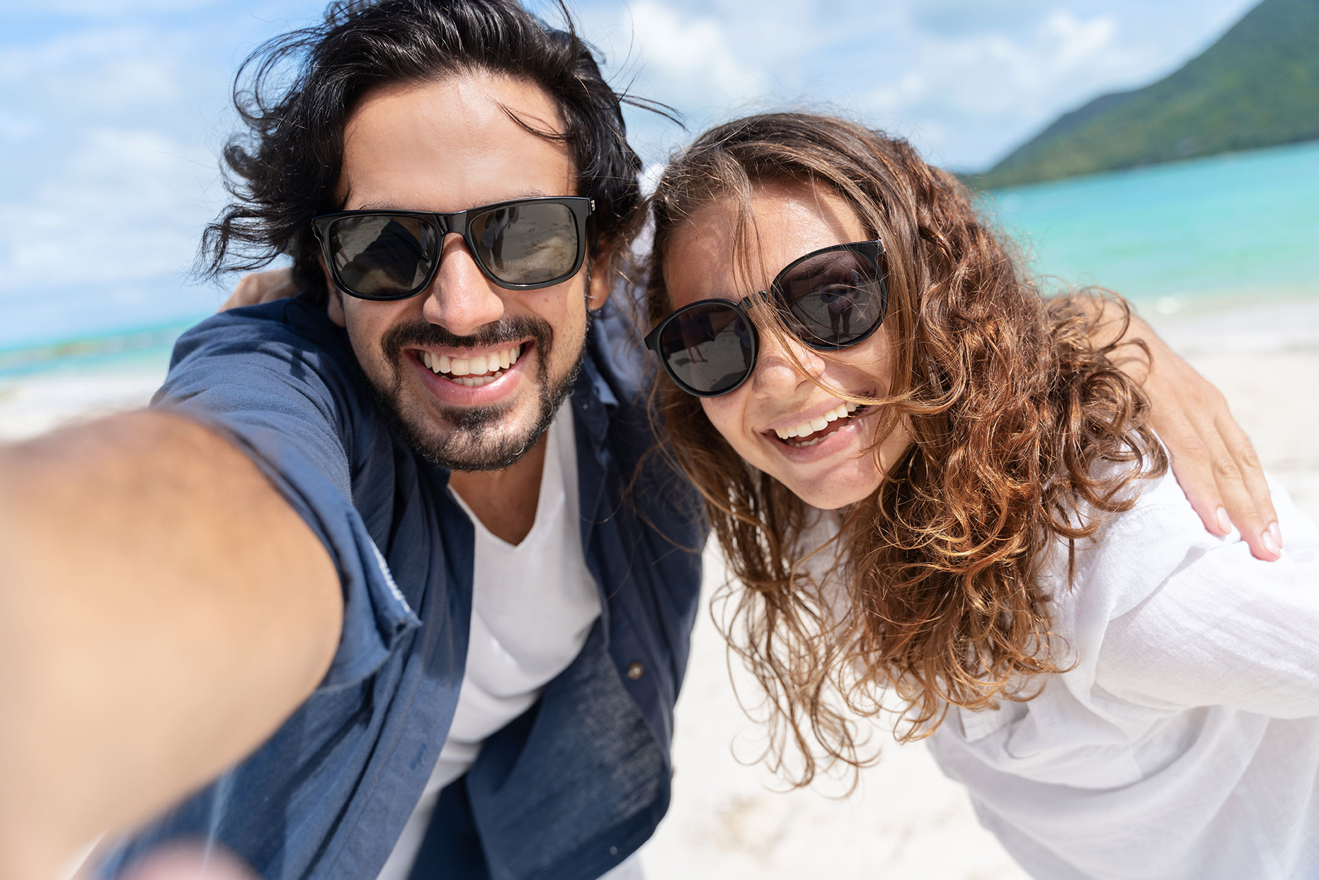 Beach vacation couple taking selfie photograph using smartphone.
