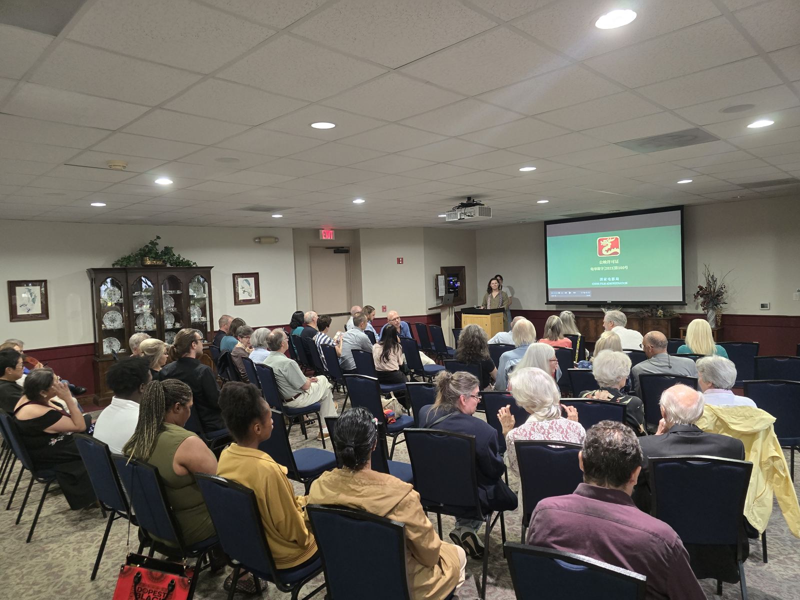The audience seated in rows as the title card for The Little Ring comes up on screen.