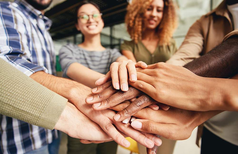 Team stacking hands symbolizing teamwork and unity in cannabis project human resources.