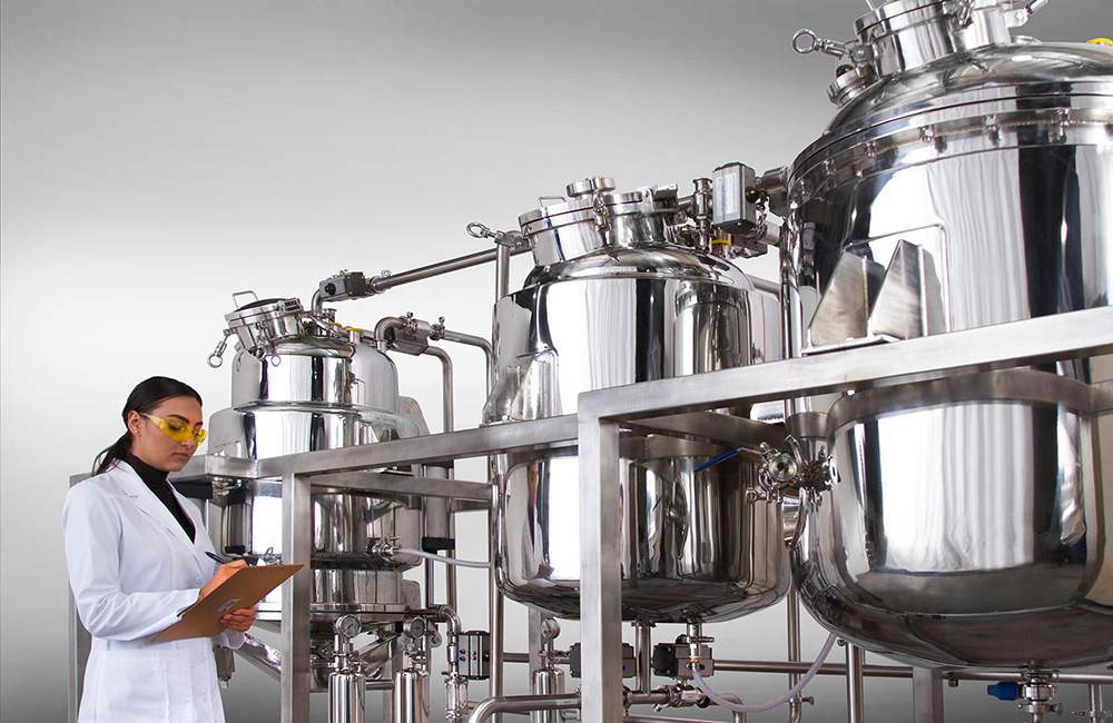 Scientist inspecting stainless lab equipment for cannabis licensing and compliance.