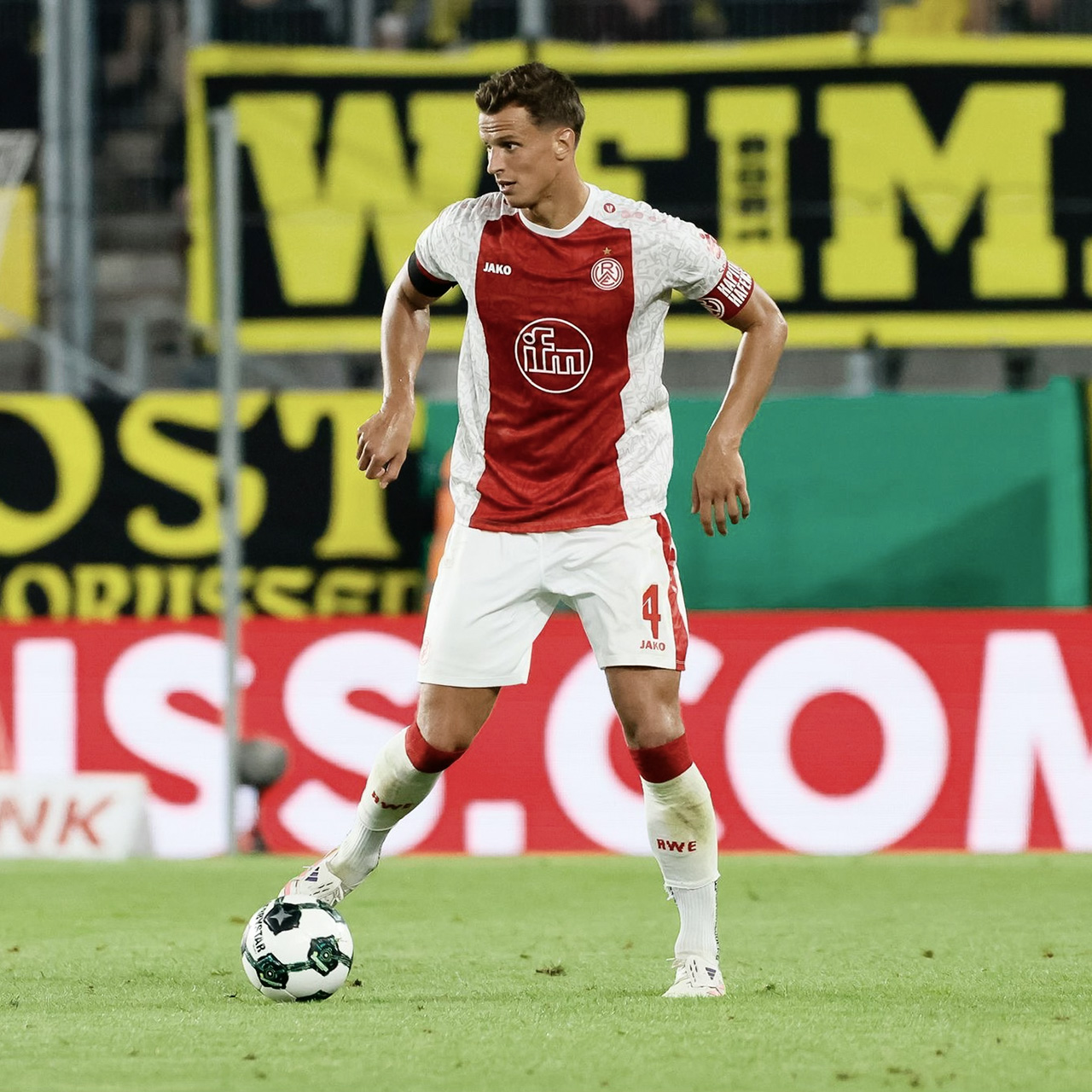 Fußballspieler im weißen und roten Trikot von Rot-Weiss Essen am Ball während eines Spiels.