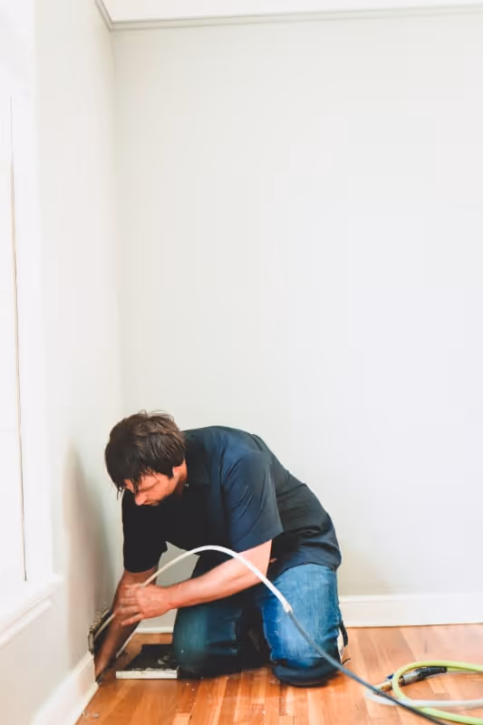 person putting hose in duct to clean