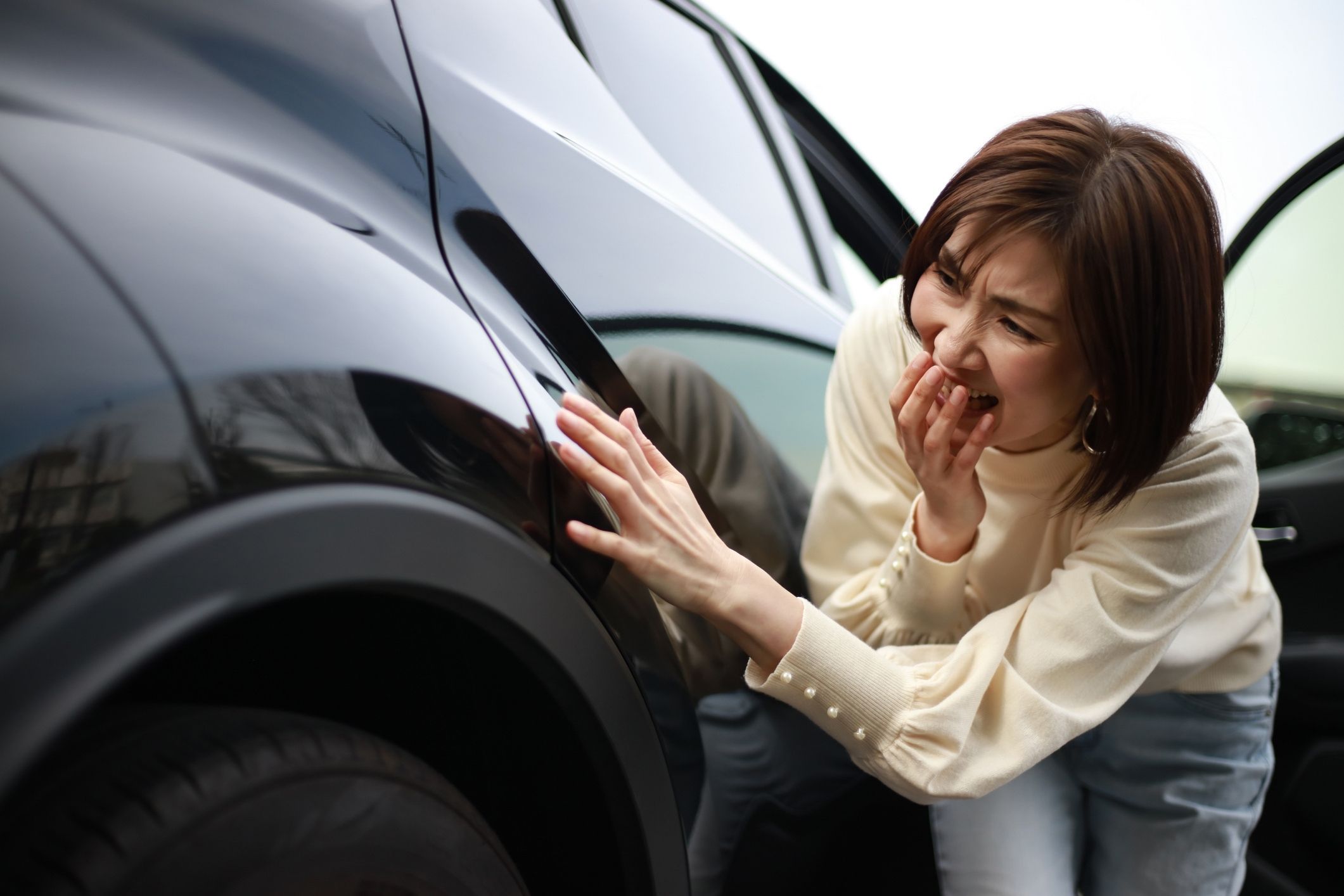 Woman inspecting car damage after a crash, representing the role of a Boynton Beach car accident attorney in helping injured drivers with claims.