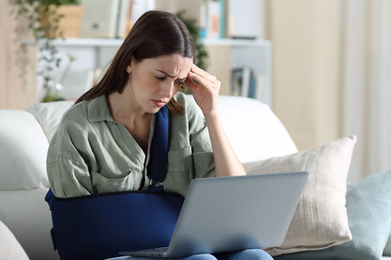 Injured woman reading on a laptop, representing those seeking help from a Boynton Beach personal injury lawyer.
