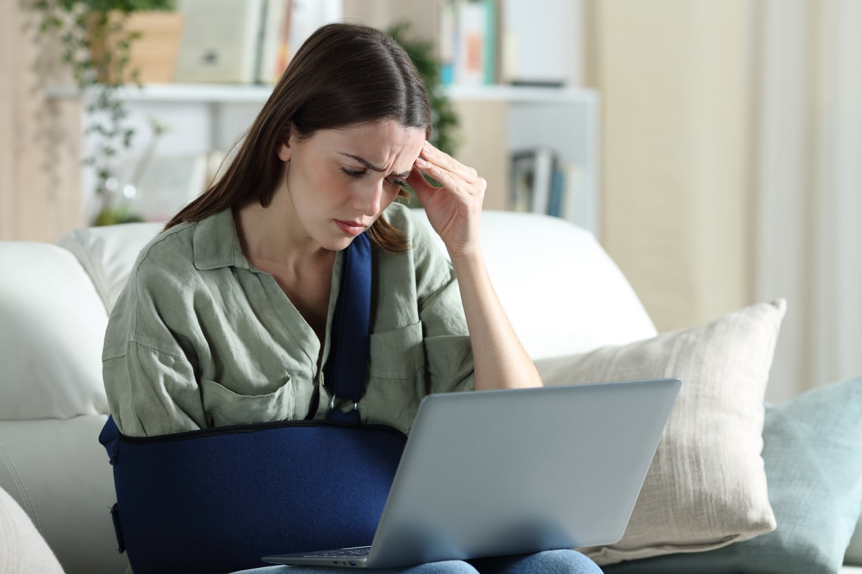 Injured woman reading on a laptop, representing those seeking help from a Boynton Beach personal injury lawyer.