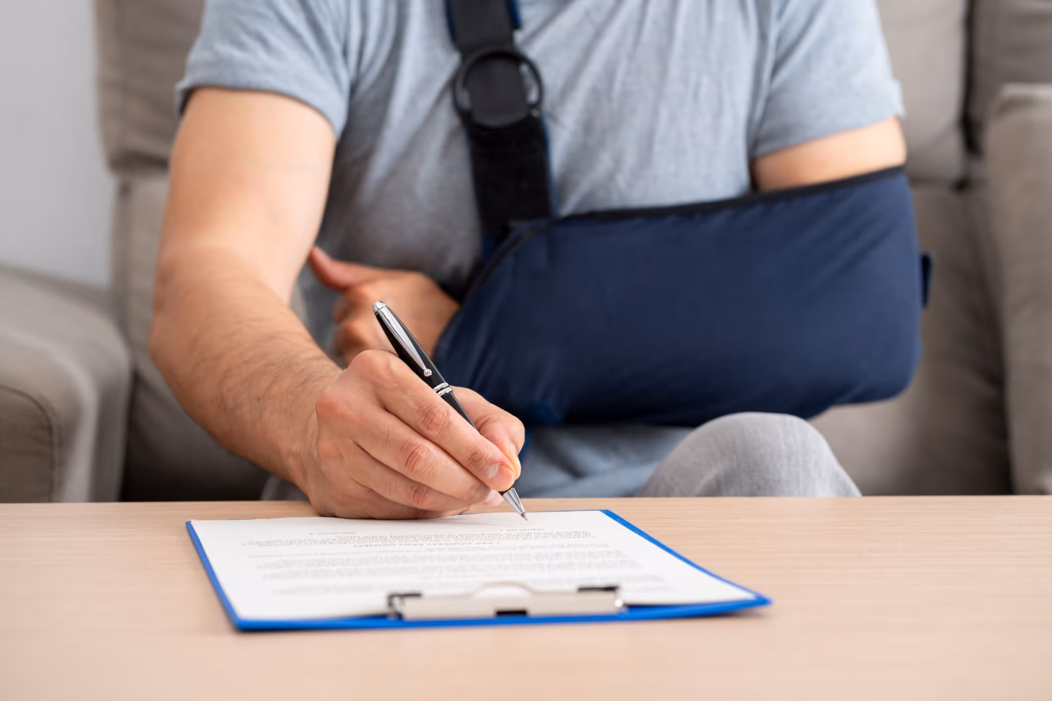 Injured man with arm in sling signing documents at home, consulting with a Apopka personal injury attorney.