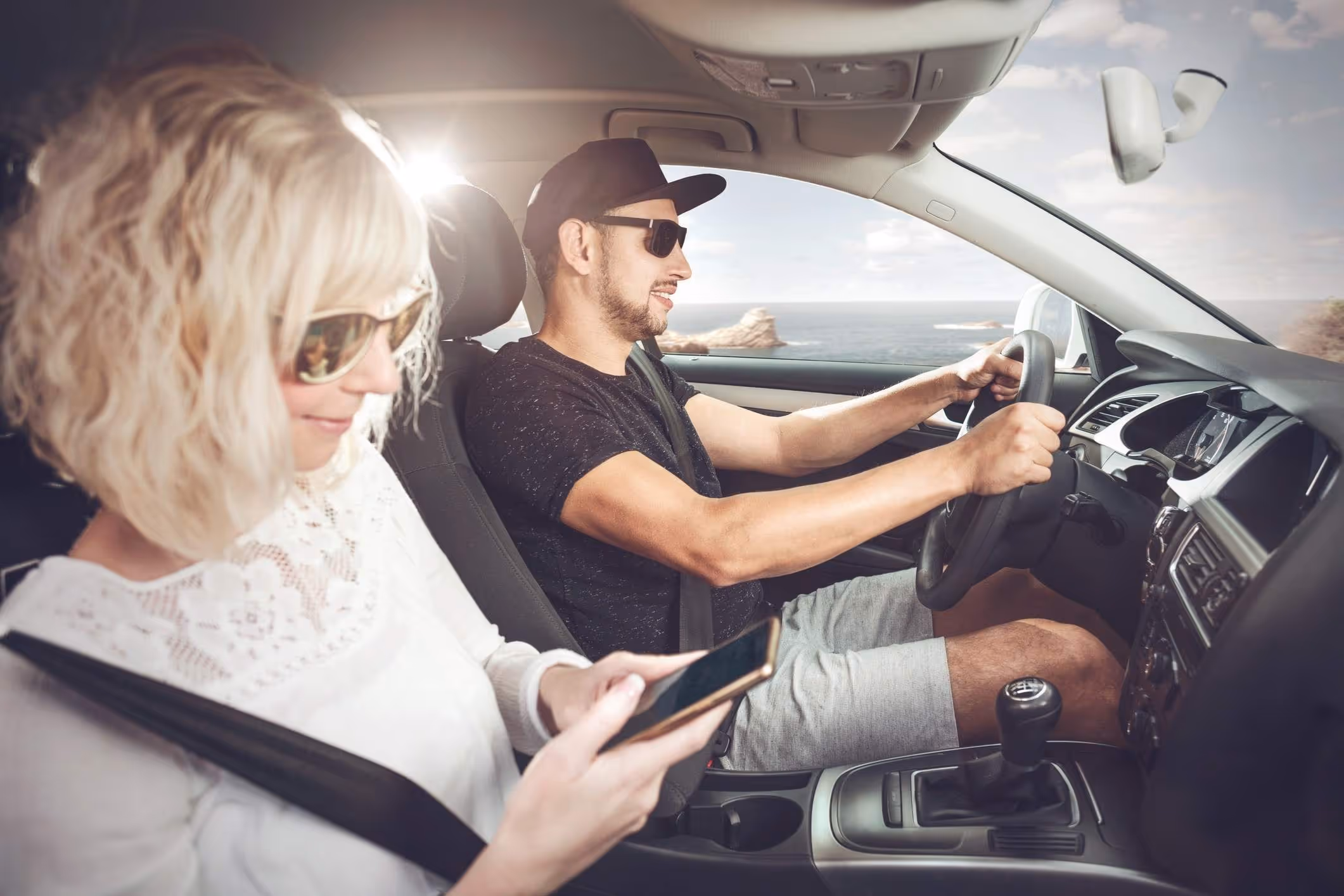 Couple driving along coast illustrating long distance driving safety tips for road trips.