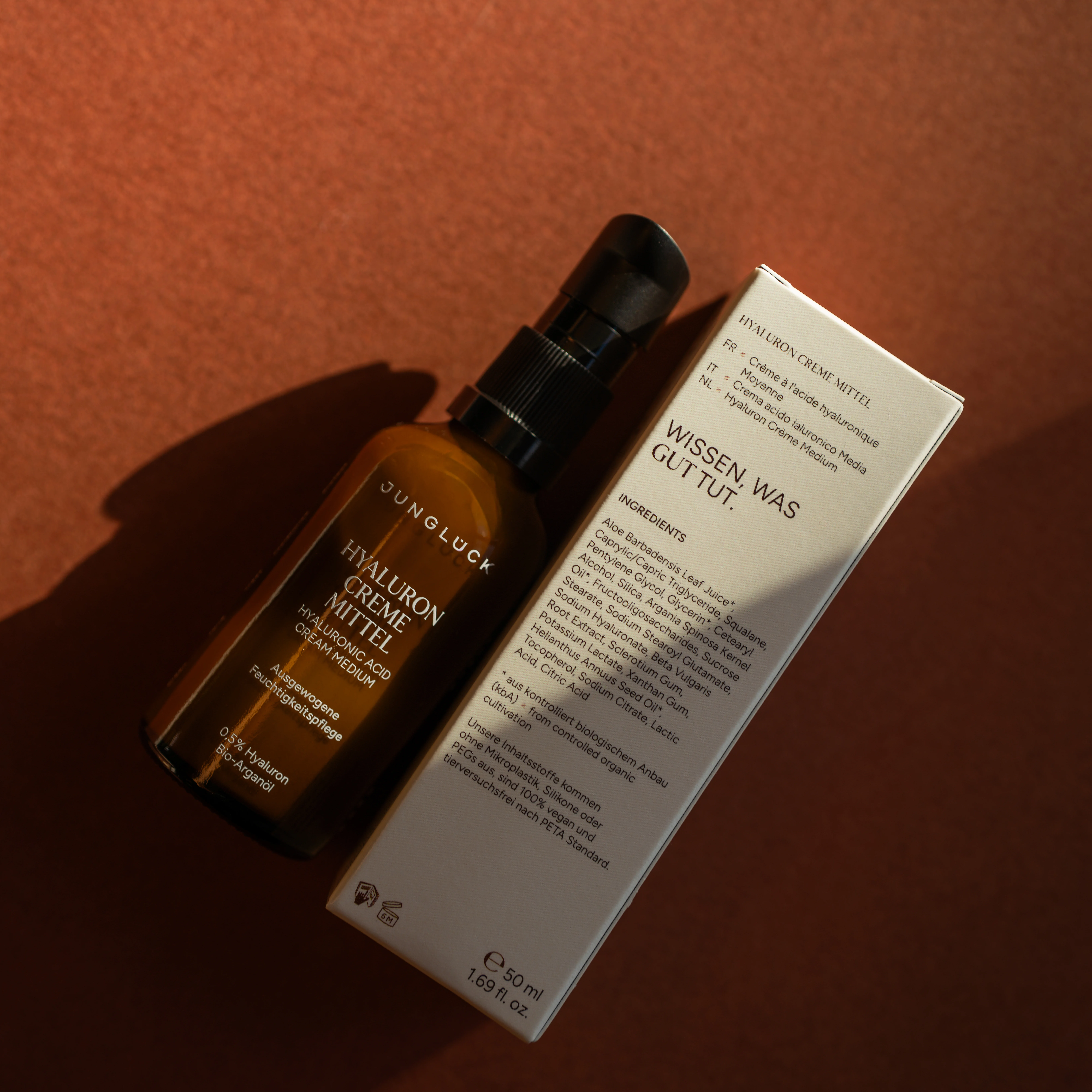 Junglück Hyaluron Creme Mittel bottle and box with ingredients list on a brown surface.