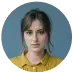 Portrait d'une personne aux cheveux foncés portant un t-shirt jaune sur fond bleu