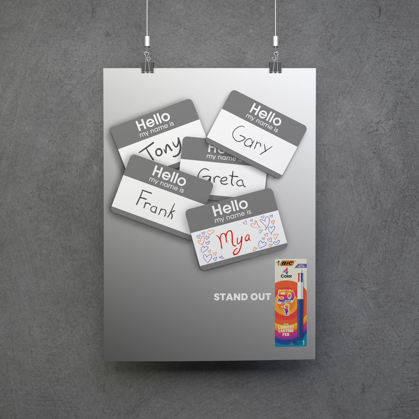 A grey wall with a picture of several name tags with names written in grey but one is written in rainbow colored ink