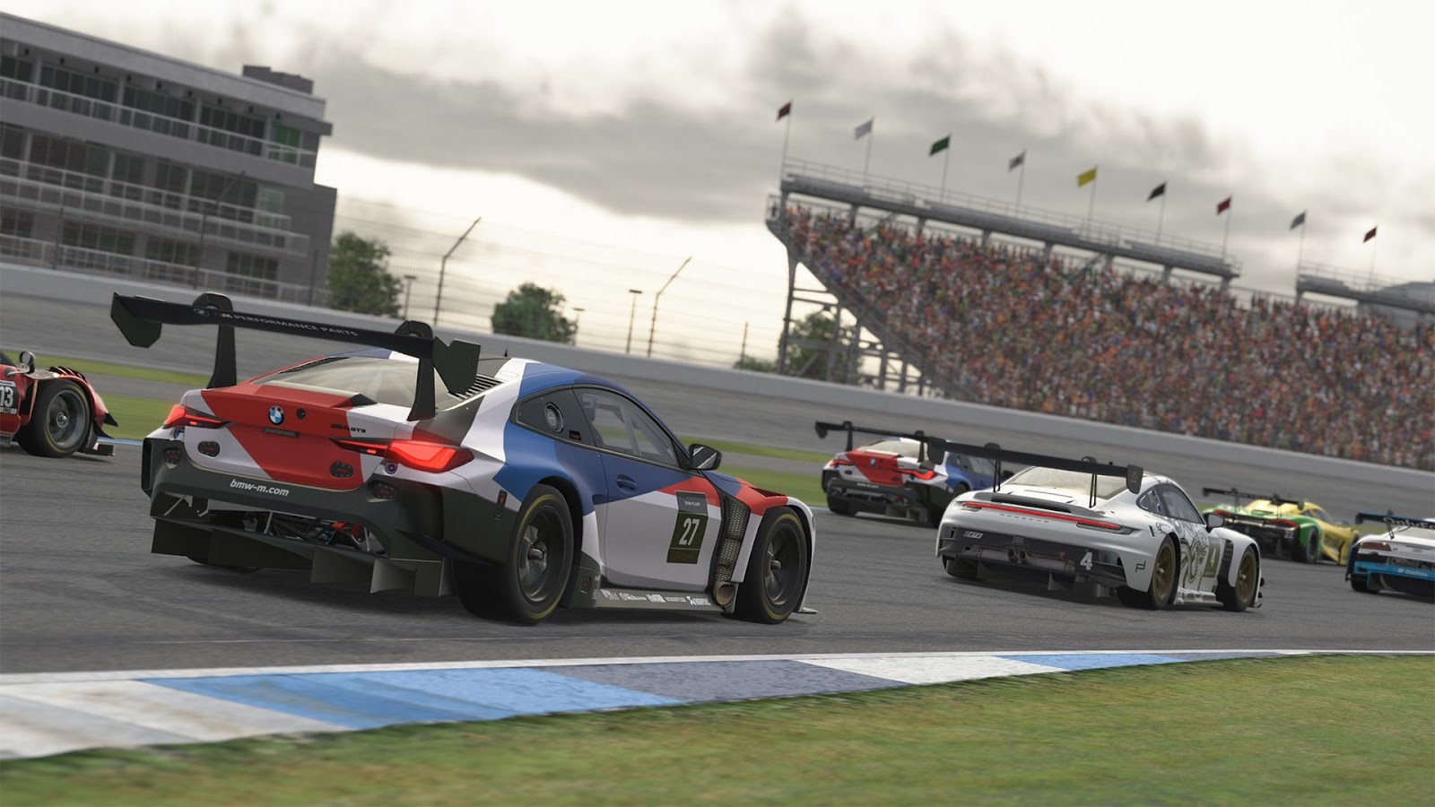 iRacing cars racing along a track with fans in the stands behind
