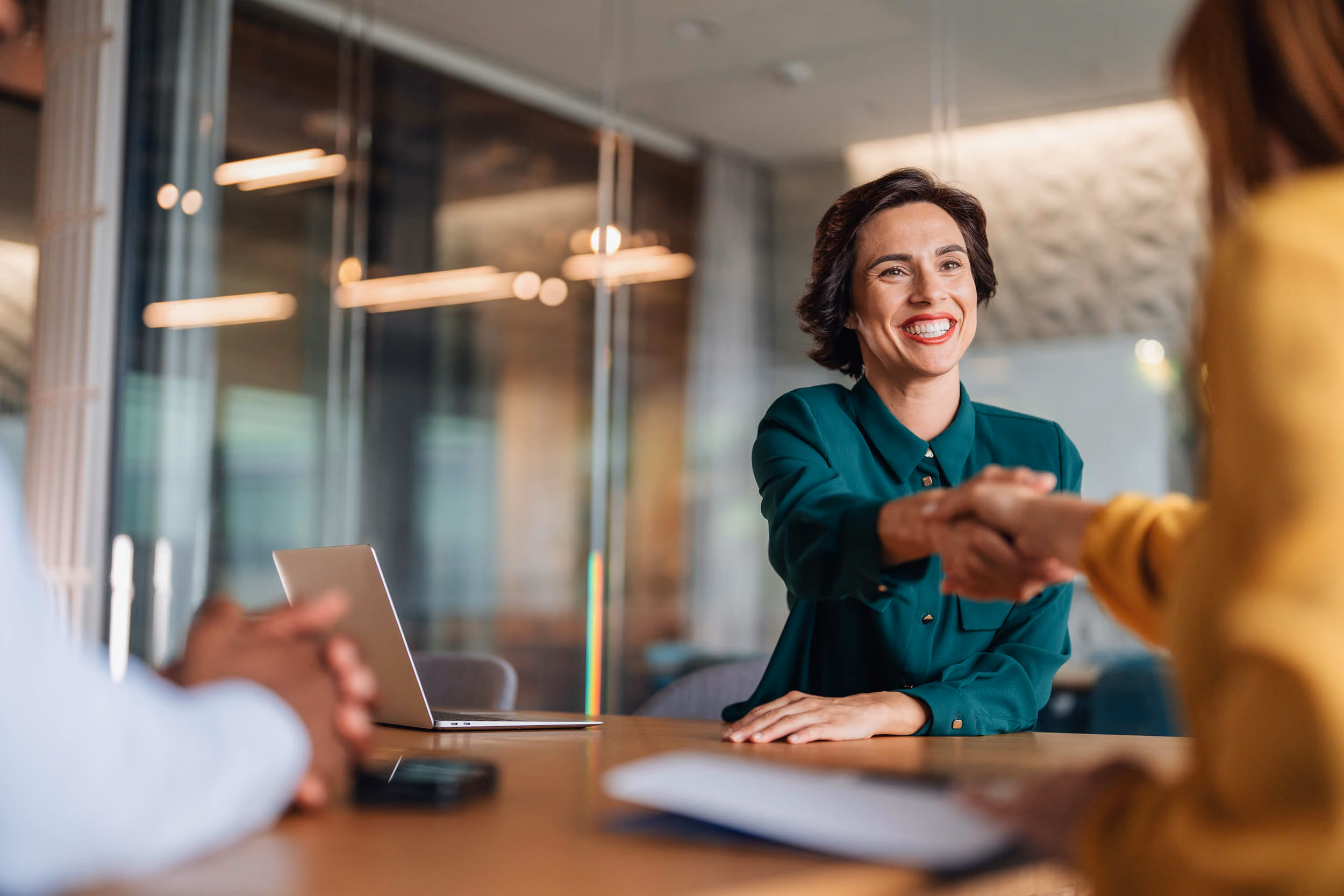 Two business professionals shaking hands across a desk