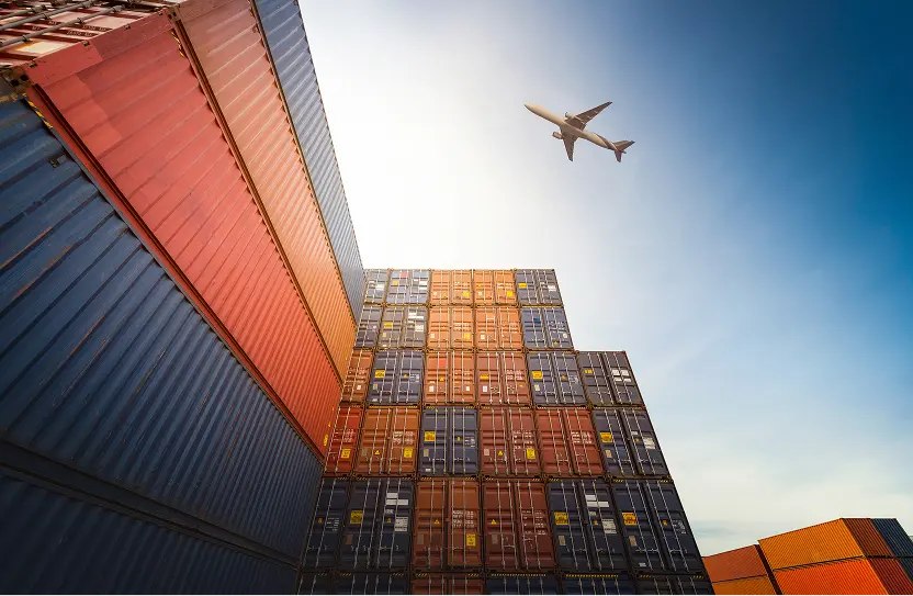Image of a plane flying over shipping containers