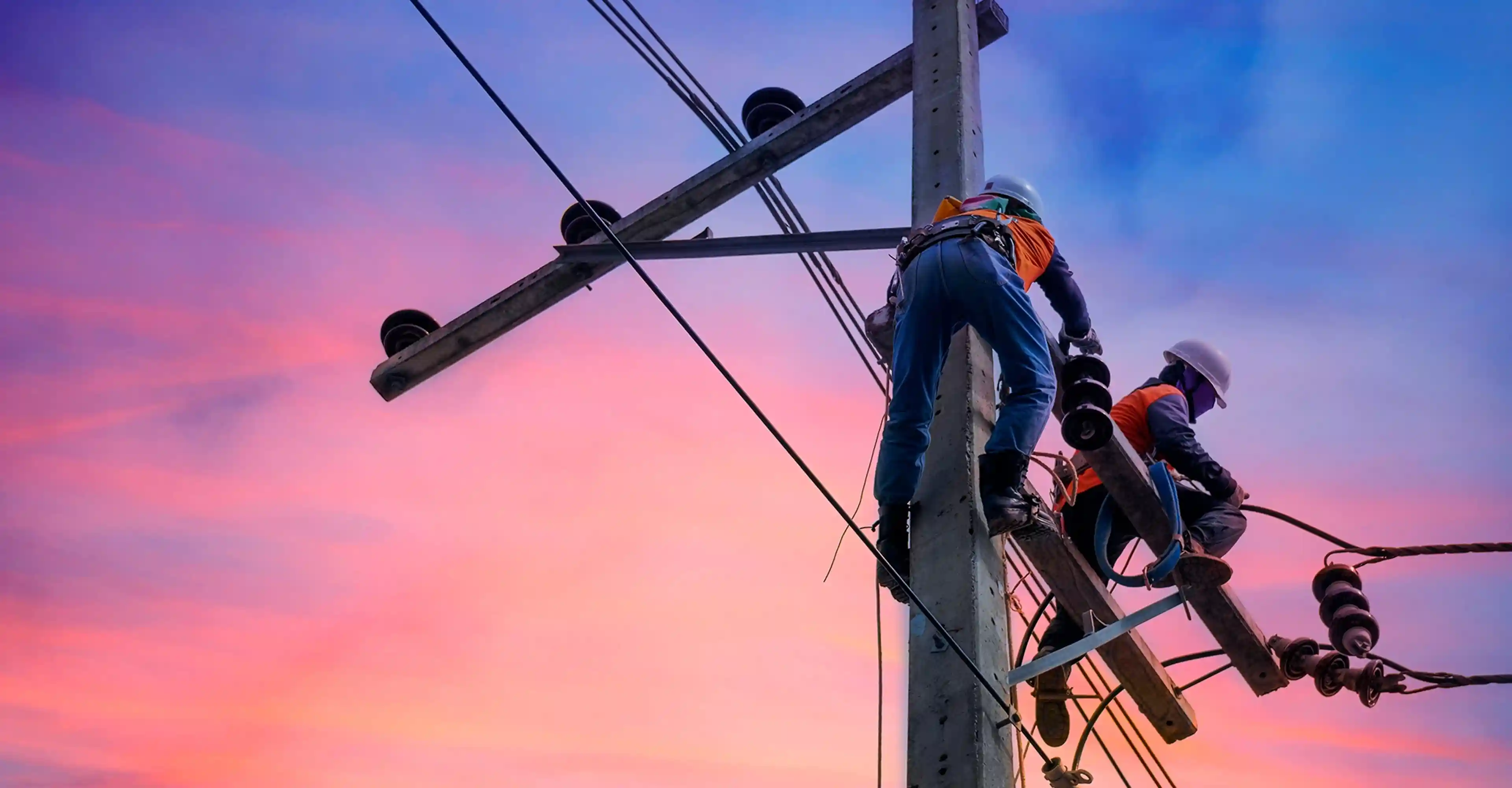 Two repairmen working with safety gear on an electrical pole