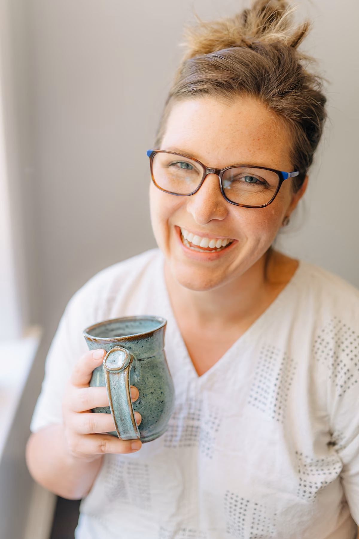 Cute woman holding handmade pottery with glasses smiling. 