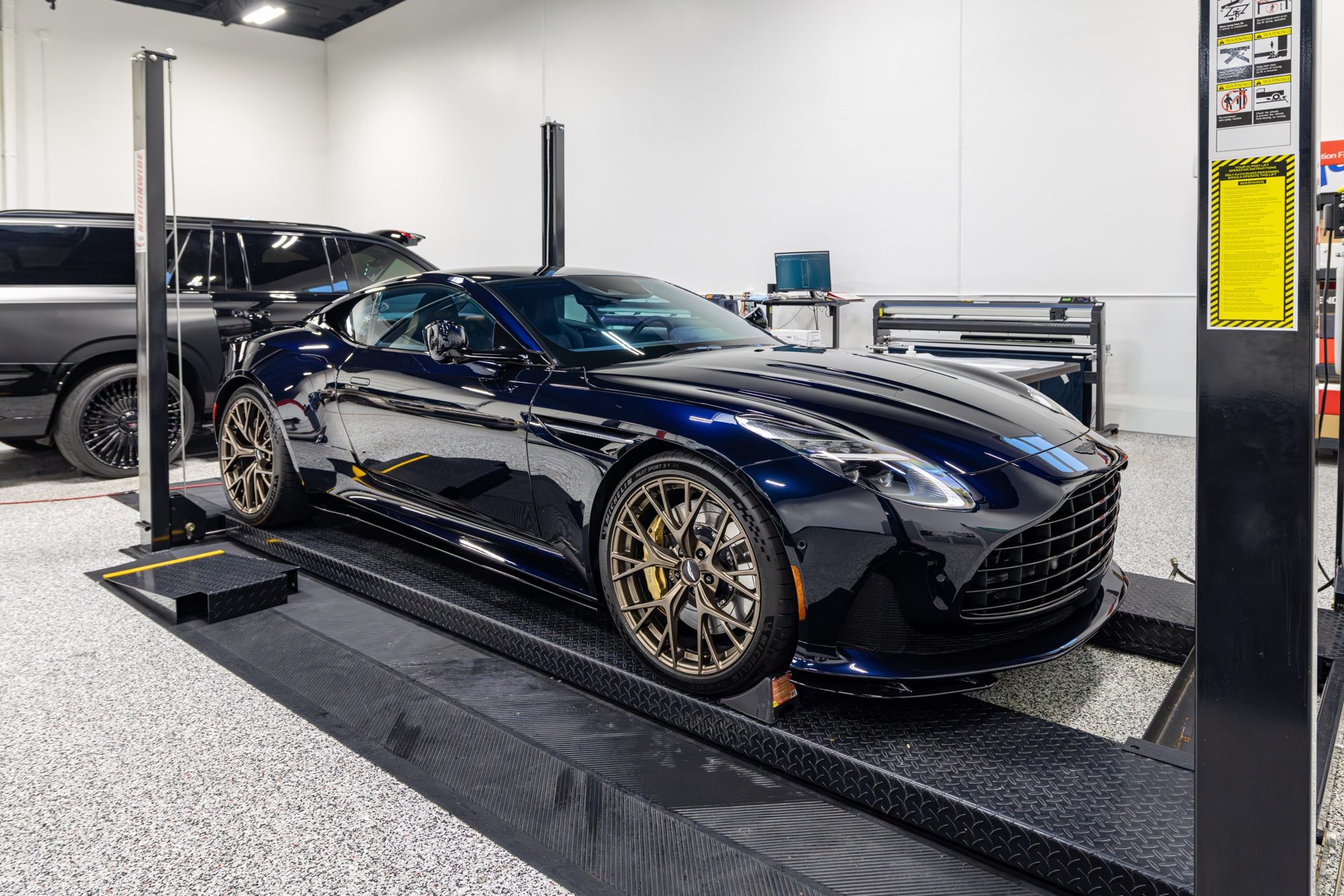 Navy Aston Martin DB12 on the lift at Detail 2 U's Rancho Cucamonga facility