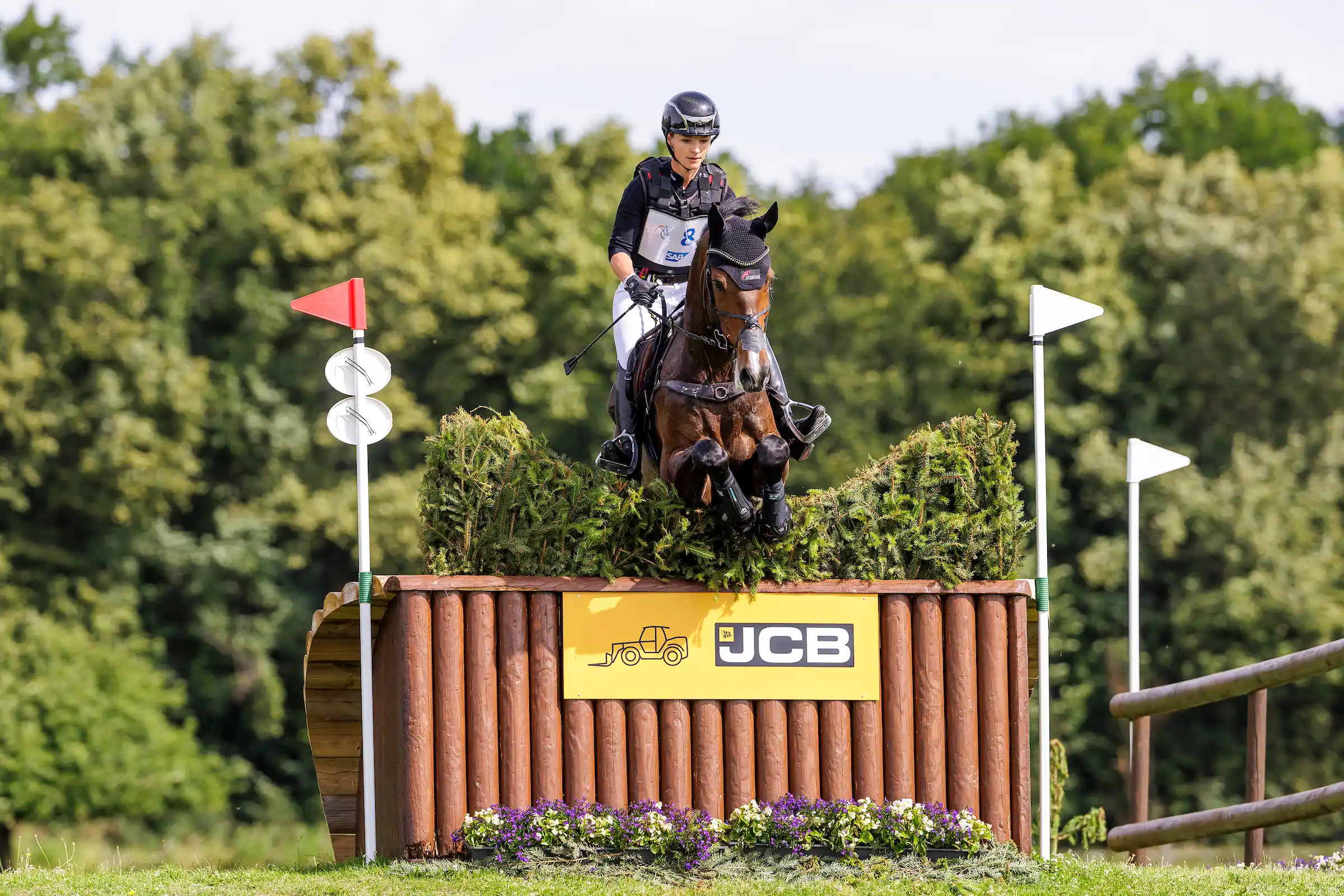 "Eventing rider and horse tackling a cross country jump at a competition, showcasing skill, safety equipment, and the challenge of solid obstacles in eventing.