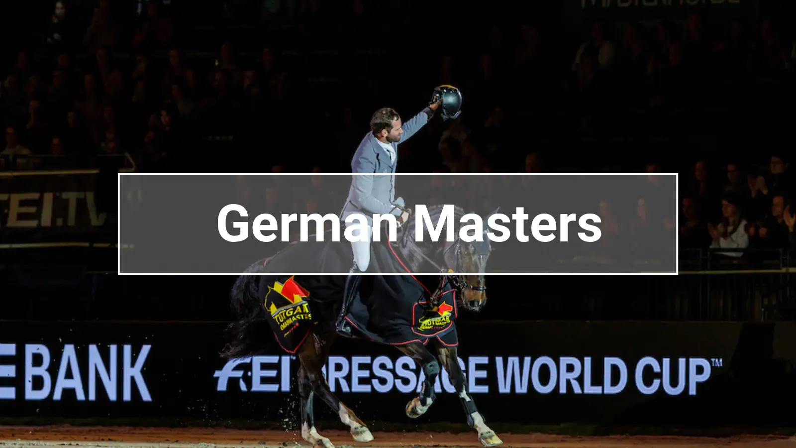 A rider celebrates at the Stuttgart German Masters in the Hanns-Martin-Schleyer-Halle atop the prize ceremony horse, with the FEI Dressage World Cup logo in the foreground.