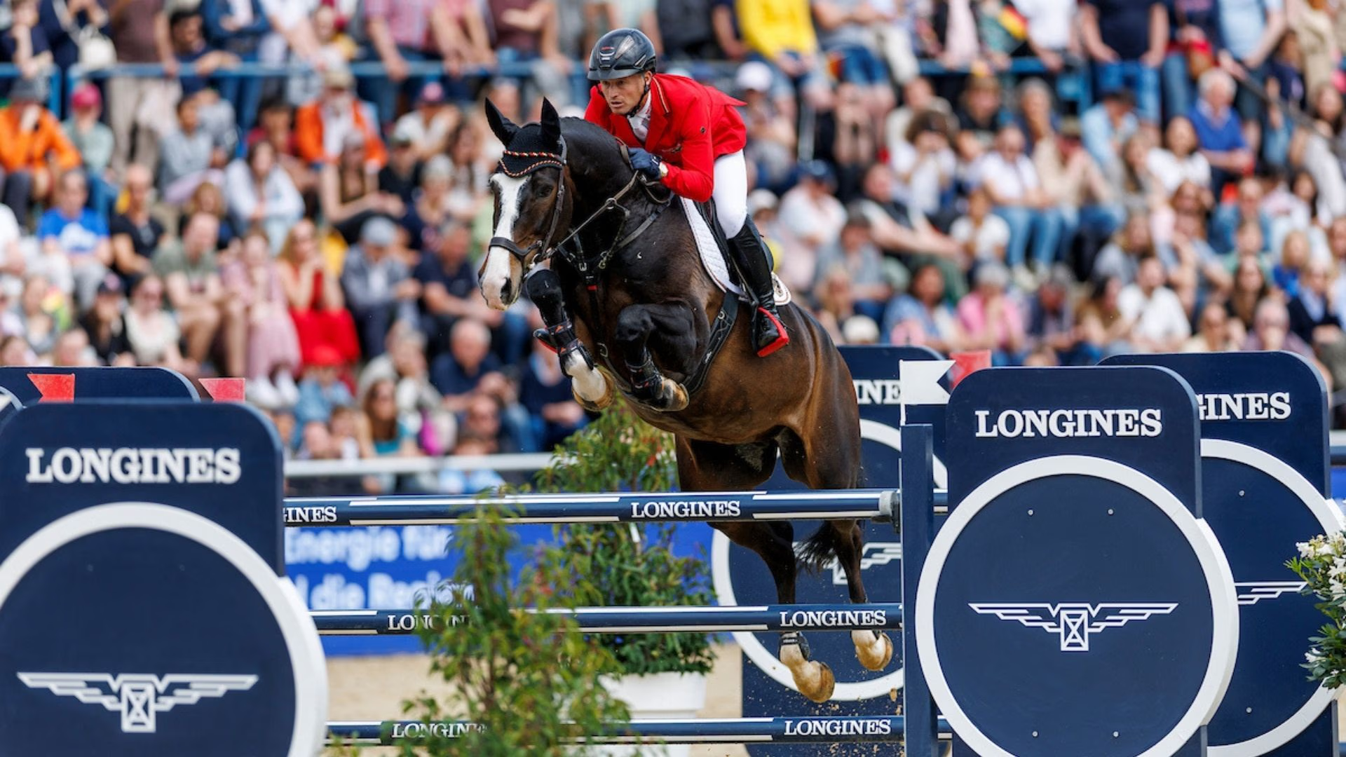 Springreiter im Parcours der Longines League of Nations™ mit Longines-Hindernissen und Publikum im Hintergrund.