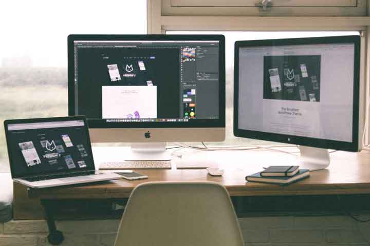 Desk with two desktop computers and laptop