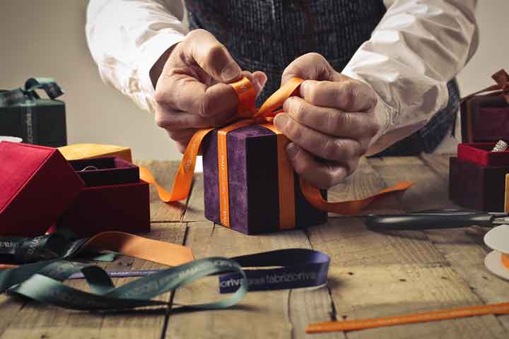 man's hands wrapping gifts on craft table