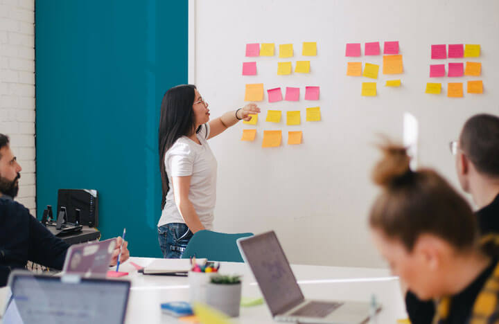Strategy meeting with woman pointing to whiteboard and sticky notes