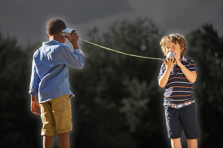two boys playing with tin can telephone