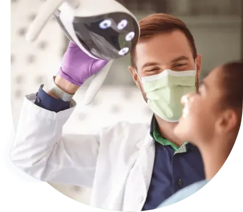 Ein Zahnarzt richtet die Lampe auf den Mund seiner Patientin.