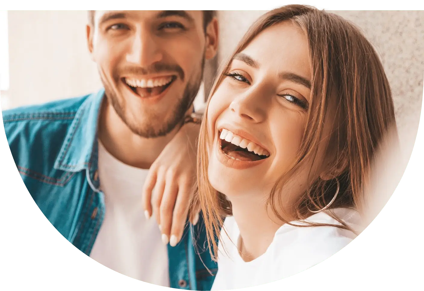 Ein Mann und eine Frau lachen fröhlich in die Kamera und zeigen ihr strahlendes Lächeln.