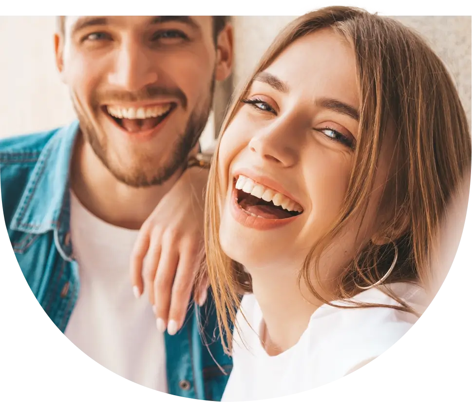 Ein Mann und eine Frau lachen fröhlich in die Kamera und zeigen ihr strahlendes Lächeln.