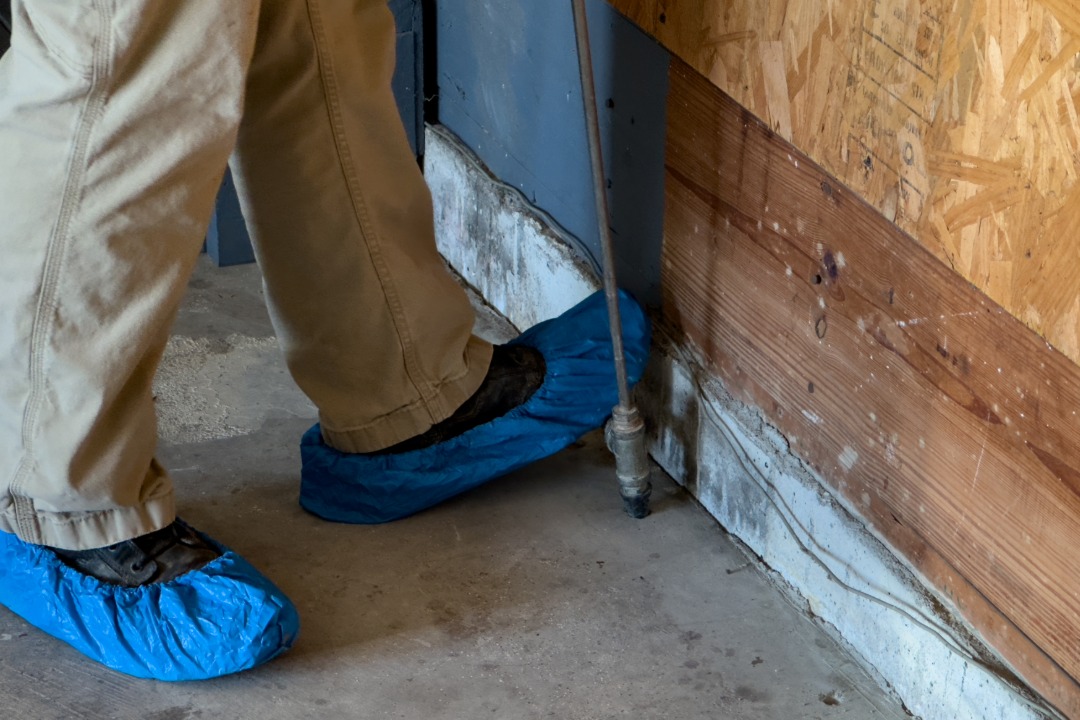 Professional applying a liquid termite treatment along a home's foundation