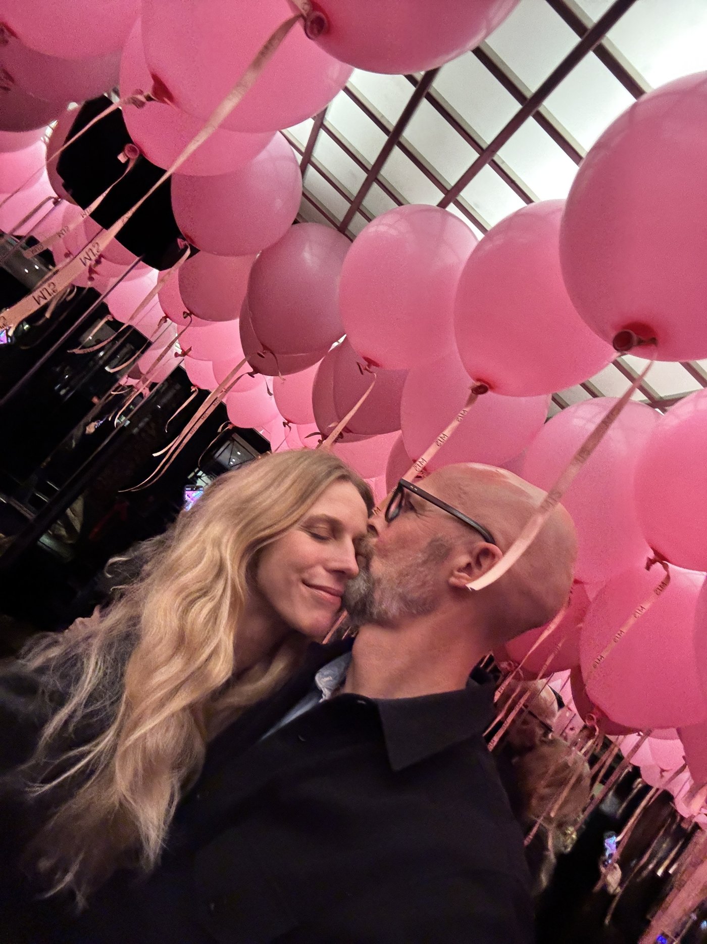 Peter Sorgenfrei with his partner under a ceiling of pink balloons