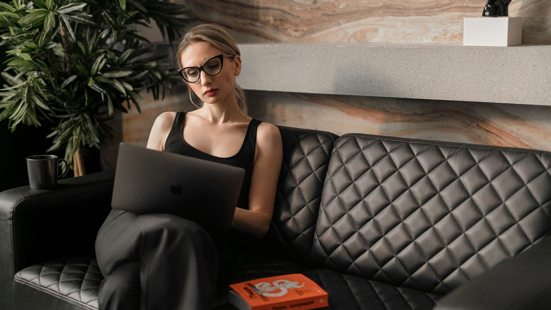 Eine Frau sitzt auf einer Couch und verkauft digitale Produkte.