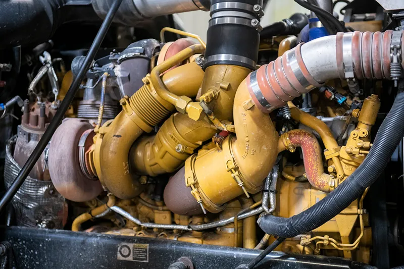 CAT diesel engine with exposed turbocharger and intake components during heavy-duty repair service.