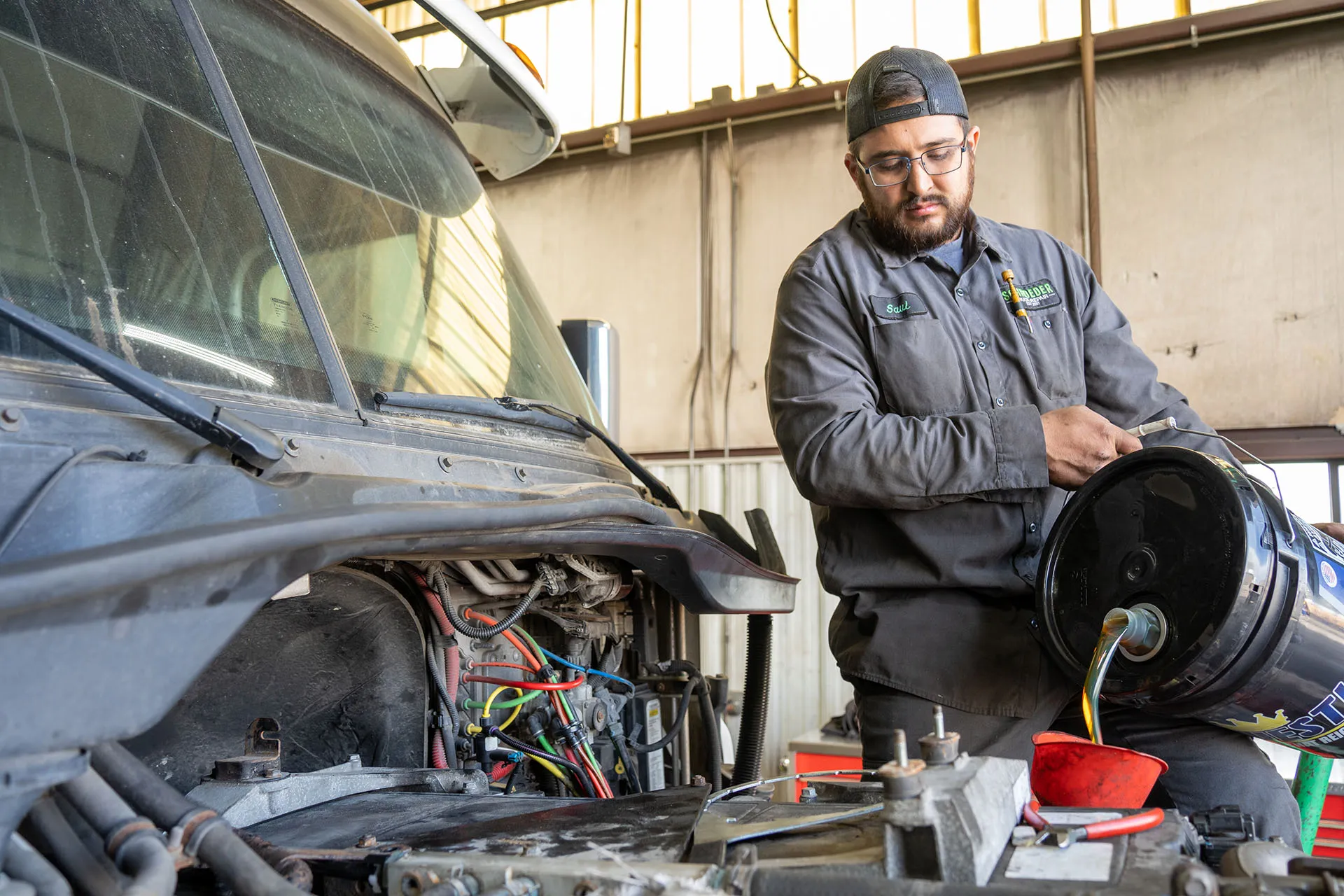 Mechanic pouring fluid at Schroeder Truck Repair