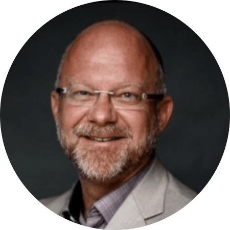 Smiling man in a white t-shirt and black quilted vest holding and using a tablet.