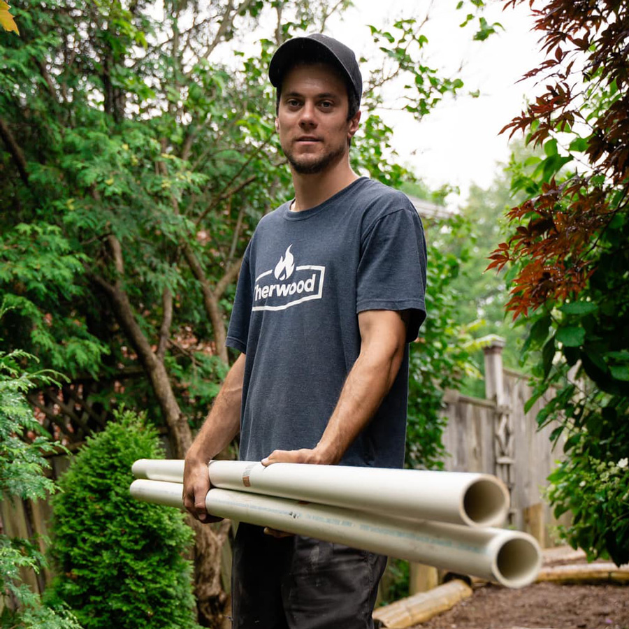 Therwood employee with branded t-shirt carrying pipes.