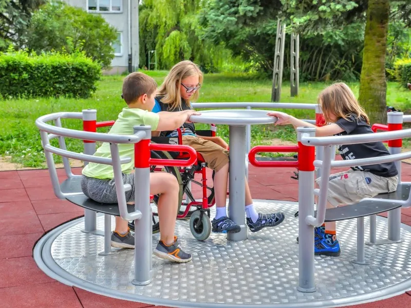 wheelchair user spinning on roundabout with friends www.mortisportandplay.co.uk