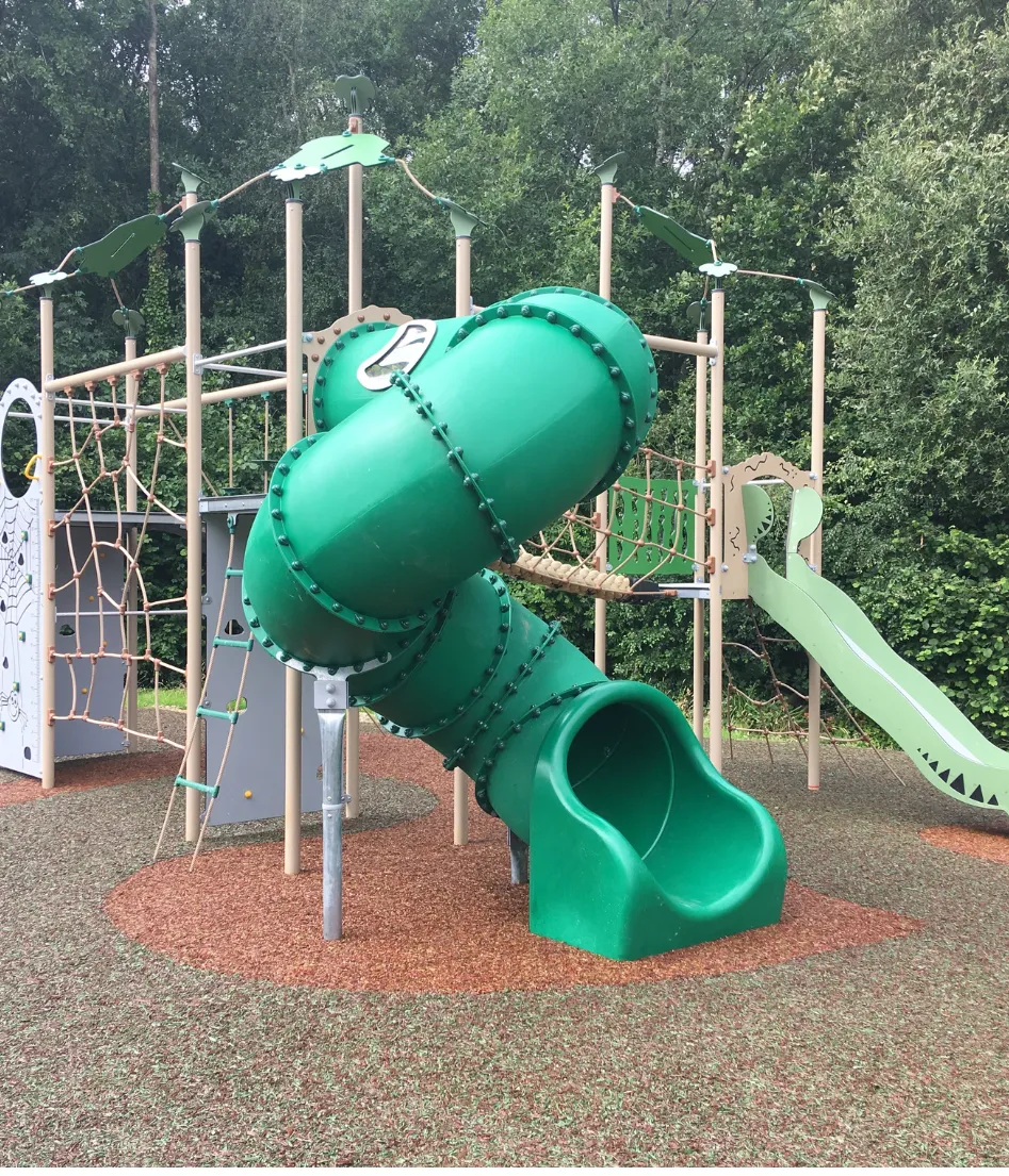 A green playground slide with a green tube on top.
