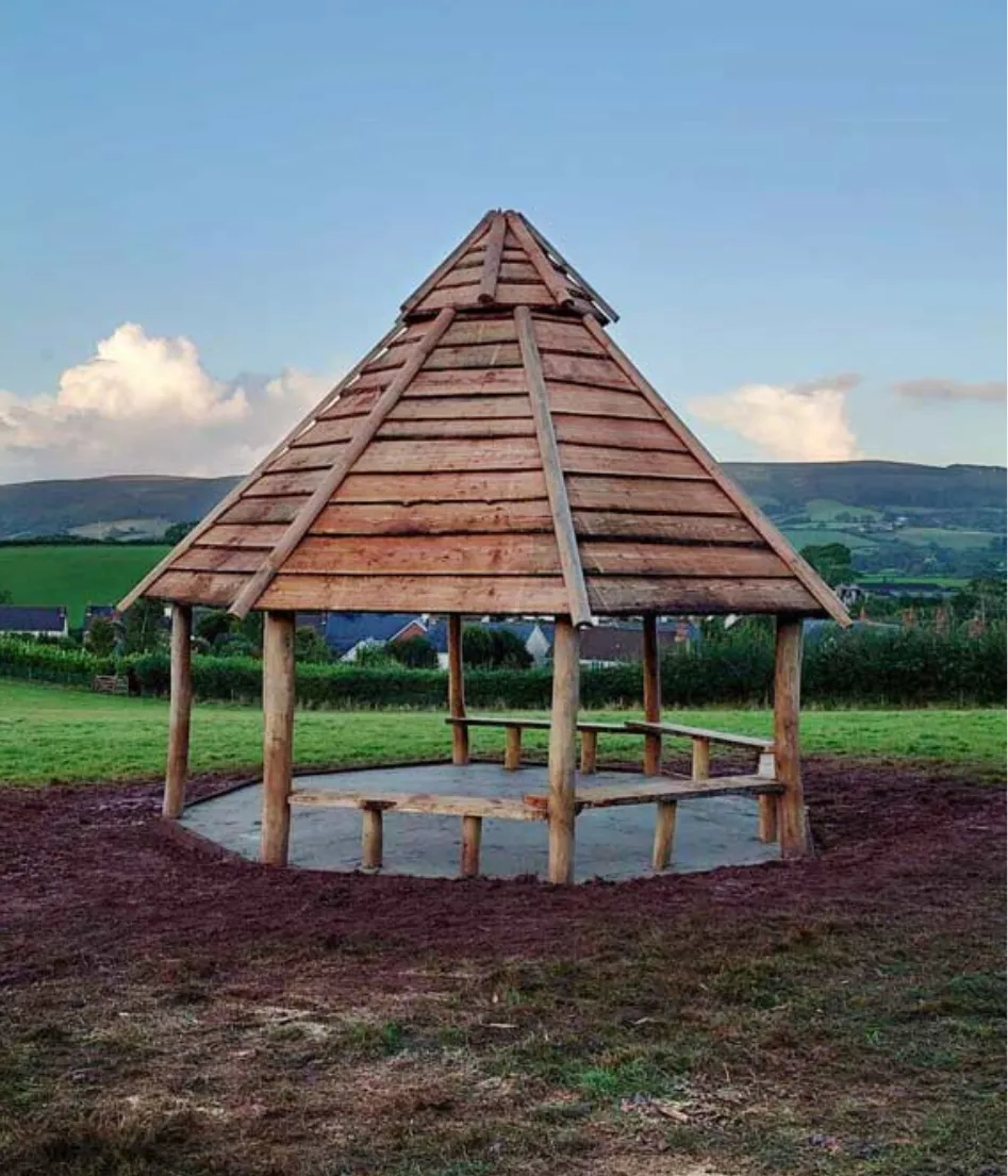 A wooden structure with a roof and a bench inside.