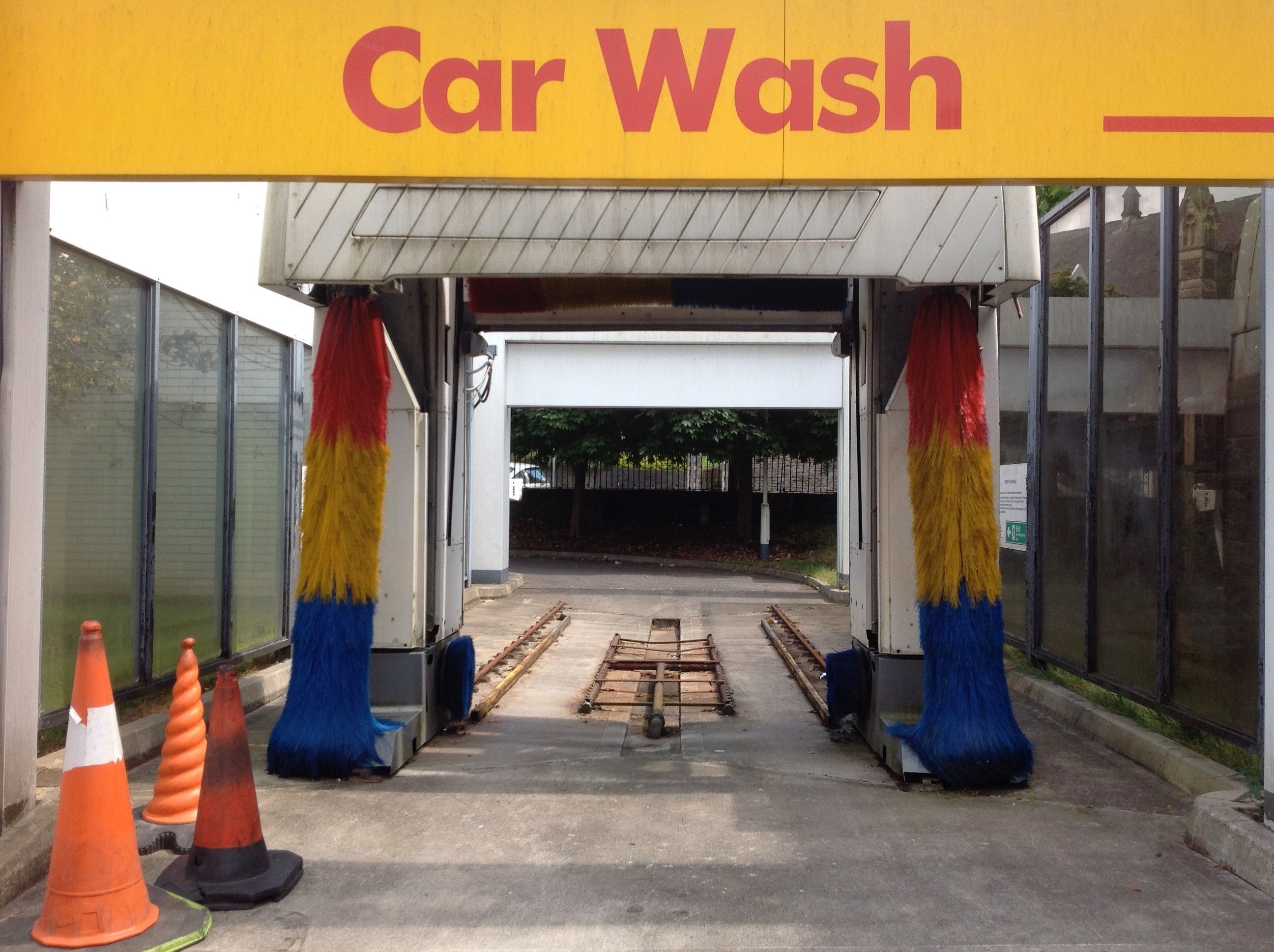 Automatic car wash entrance with colorful brushes and traffic cones.
