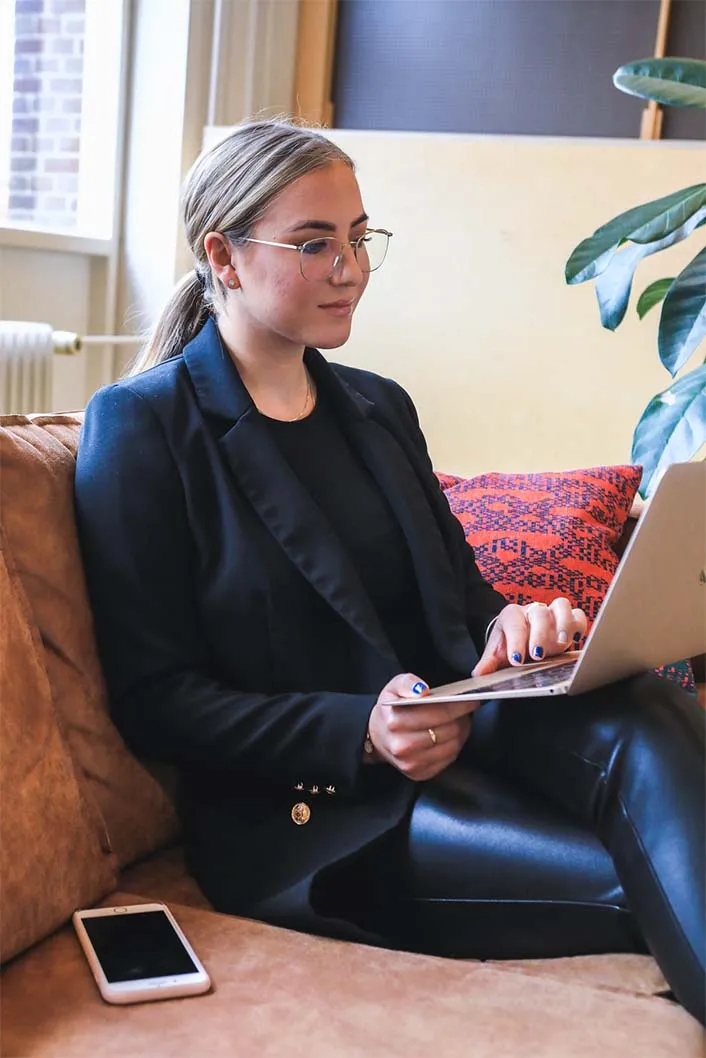 Woman on a couch learning digital skills on a laptop.