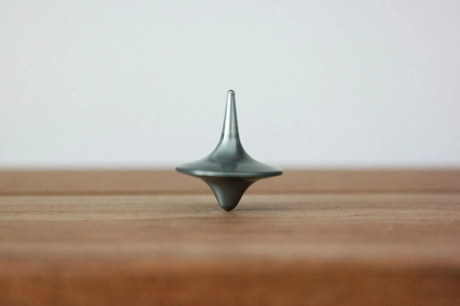 A silver spinning top on a wooden surface