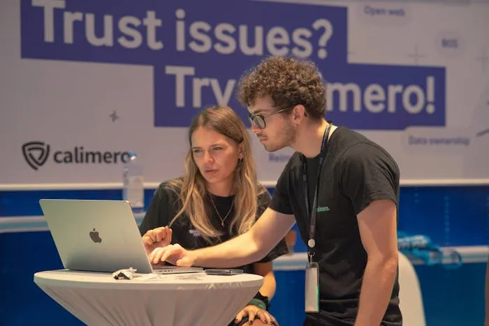 Two individuals at a booth with a laptop