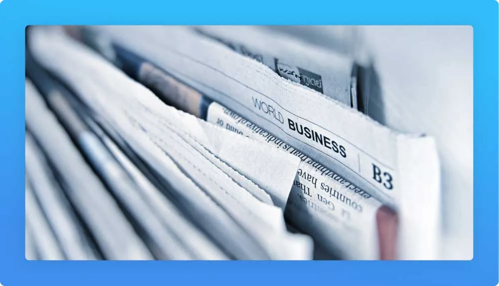 Stack of newspapers in focus with "WORLD BUSINESS" section visible.