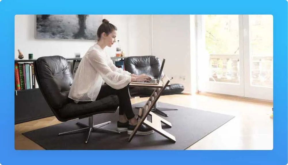 Living room, two black chairs, young woman sitting and working on laptop