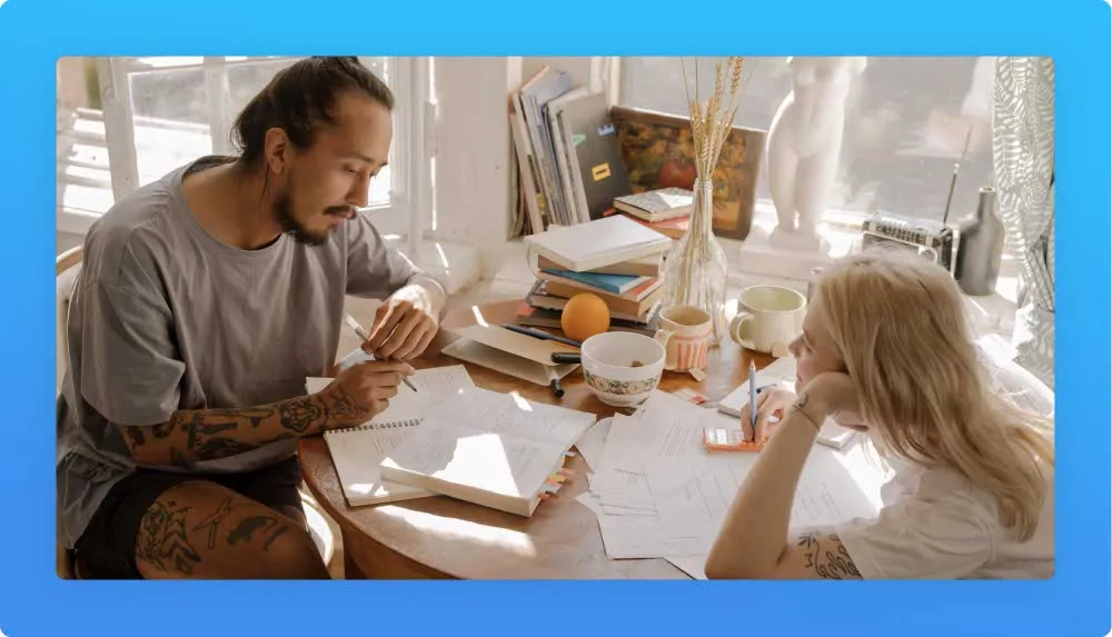 A young couple seated at a table taking notes while considering on life and career changes