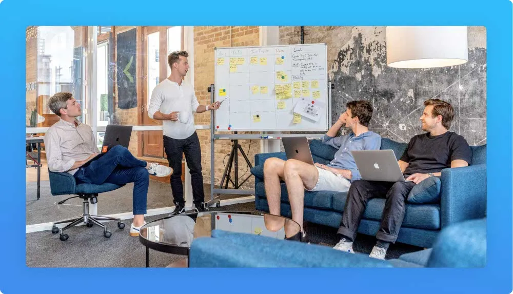 Operations manager during a meeting with his team, looking to a written white board with post-its