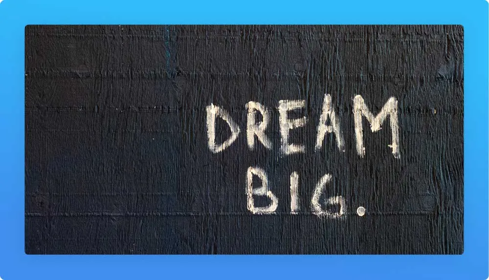 "Dream big" in pastel yellow written on a black wall 