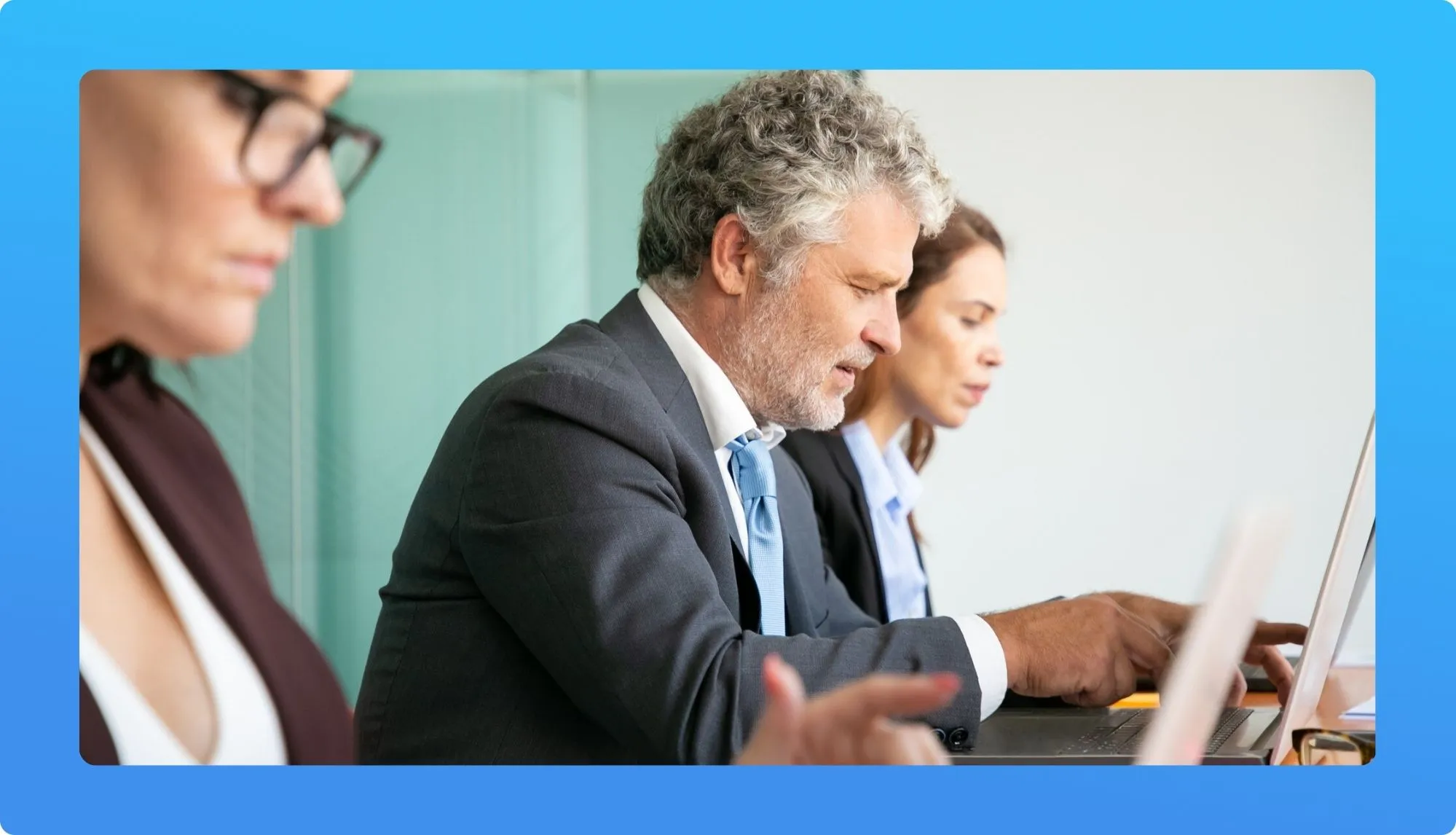 A group of professionals engaged in online learning, focused on laptops, with a collaborative atmosphere.